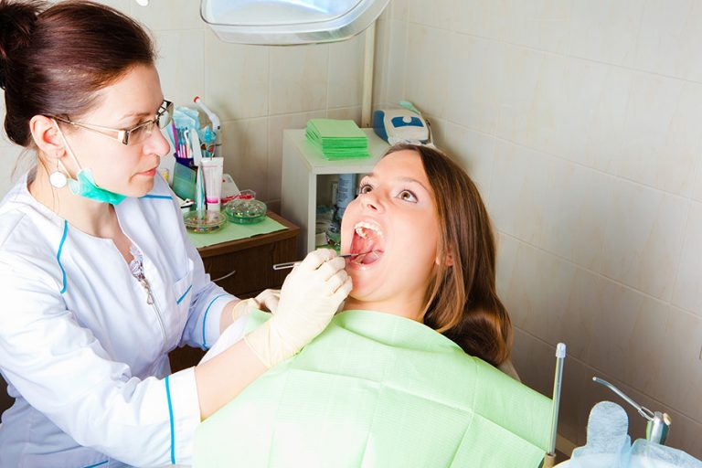 woman dentist making a review of patient mouth Senior Solutions